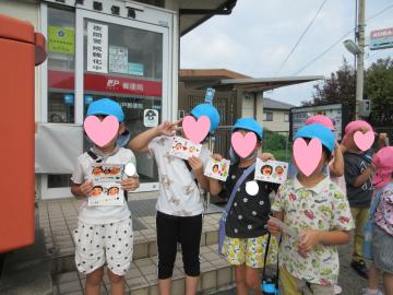 郵便局前で園児たちがハガキを持っている様子
