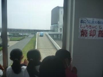 焼却場へ進むごみ収集車を窓から見ている子どもたちの様子。