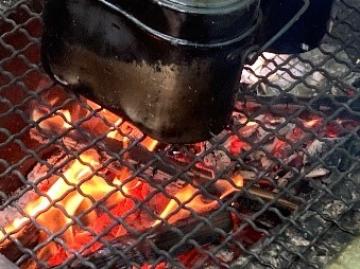炭火の上に飯盒を置いている写真