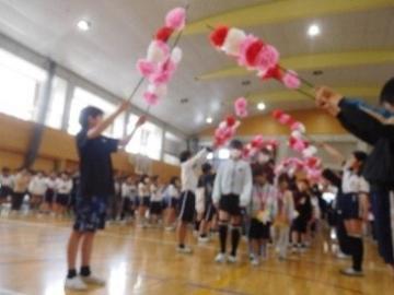 高学年が持つ花のアーチを1年生がくぐっている様子