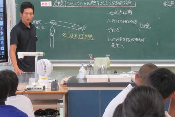 教室内で8年生が教員から実験についての説明を聞いている様子