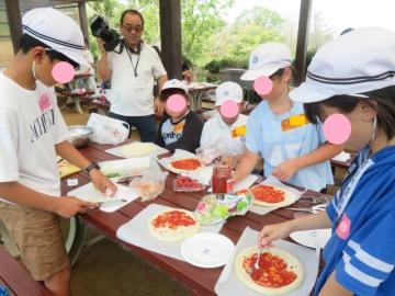自分のピザをトッピングする5年生