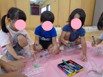 幼児がペットボトルに大根の絵をかいているところ