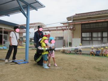 消防士の方と一緒に、園児2名が放水体験をしているところ