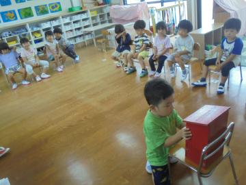 室内で幼児がポストにハガキを投函している場面