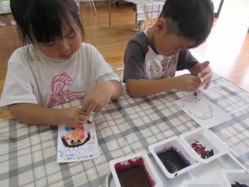 机に向かって幼児が祖父母へのハガキを描いている様子