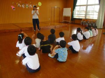 遊戯室で園長先生の話を聞く子供たち