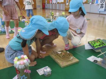 体育館で小学生の作った作品を顔を近づけて眺める子供たち