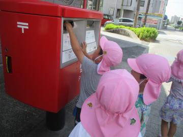 はがきをポストへ投函する子供