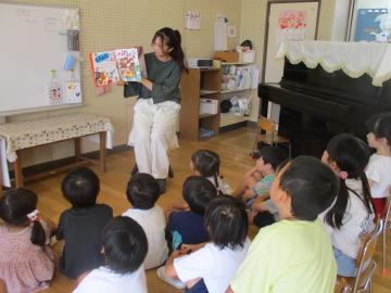 地震の絵本を読む教師と見る子供たち