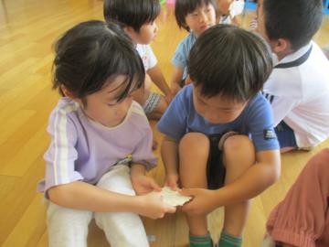 牛乳パックで作った紙を4歳児へ触らせてあげる5歳児