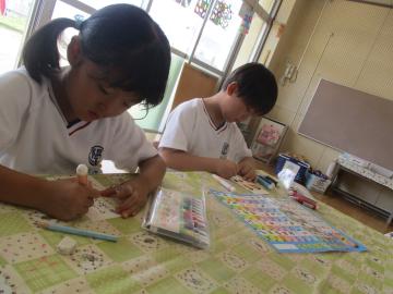 あいうえお表を見ながら祖父母への手紙をかく子供