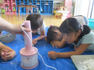 ミキサーで紙が砕かれる様子をじっと眺める子供たち