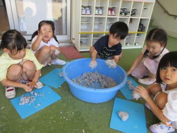 屋内で、紙が粘土に変化することを体験する園児の様子