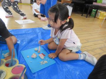 屋内で絵具を使い色を塗る園児の様子