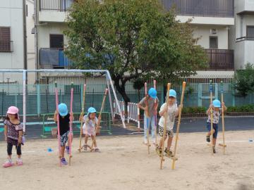 屋外で幼児が竹馬やパカポコをしているところ