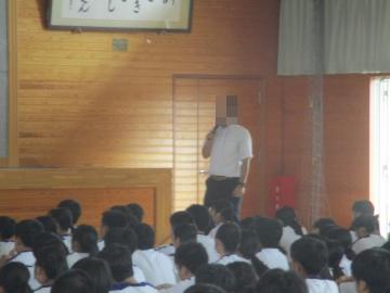 体育館の前で講師の先生がマイクを持ち、話をしています。