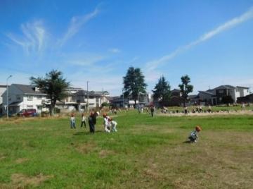 秋の青空が広がる公園にたくさんの児童がいる様子