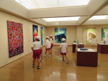 室内で壁に並んでいる大きな作品を見学する児童たちの様子