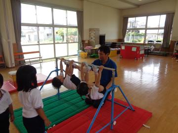 体育遊び2　きりん組が鉄棒で足抜き回りをしている様子