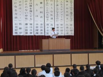 体育館の壇上に登壇し、緊張しながら説明する弁論者の様子