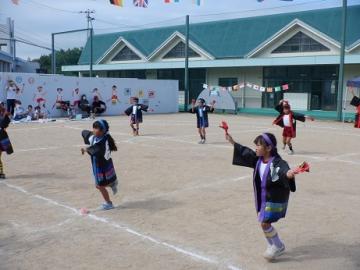 園庭で園児が鳴子を持って踊っている様子