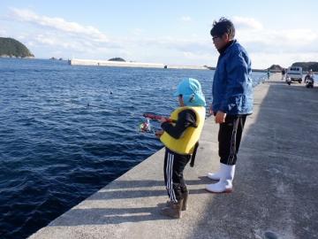 堤防で園児が魚の釣り方を教えてもらっている様子