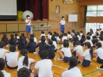 体育館において、全校集会でお別れの挨拶をする中学生の様子