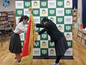 生徒会役員の交代式の様子。旗を交換する新旧の役員です。