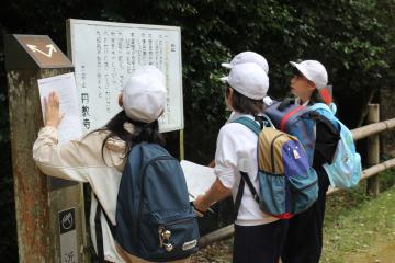 ウォークラリーをしている児童たちの様子。立て看板の文字を読んでいます。
