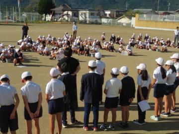 校庭で草ひきの説明をする環境委員会の様子