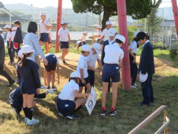 屋外で別の場所の草ひきをがんばる児童たちの様子