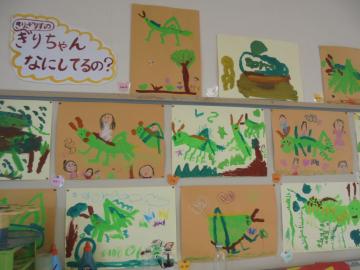 室内の壁面に園児たちが描いたキリギリスの絵を飾っている様子