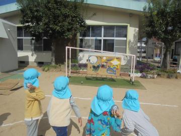 園庭で園児たちが100点を狙ってボール投げをして遊んでいる様子