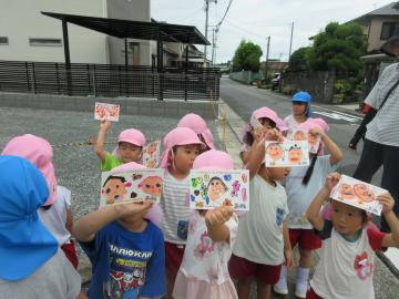 屋外で4歳児が敬老の日ハガキをかざす様子