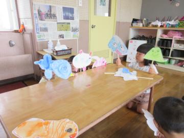 室内で太陽君とおつきちゃんのペープサートを演じる園児の様子