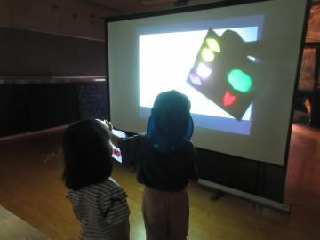 室内でプロジェクターを使い星を映す4歳児の様子