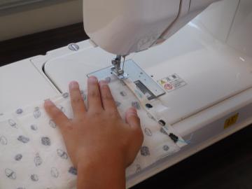 柄のある布をミシンで縫っている様子。