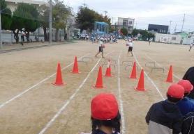 運動場にある走るコースを見ている子どもたちの様子