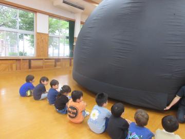 移動プラネタリウムの説明を聞く幼児
