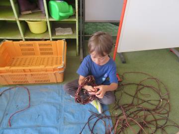 芋のつるでリースをつくる幼児