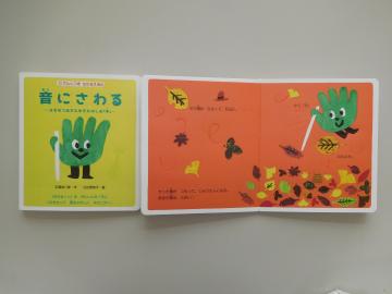 手や秋のイラストがある絵本の写真。点字がついています。