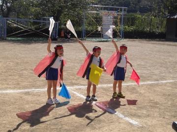 園庭で年長児が応援団になって年少児を応援する姿