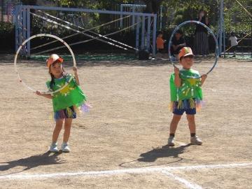 園庭で年少児がフラフープで演技する様子