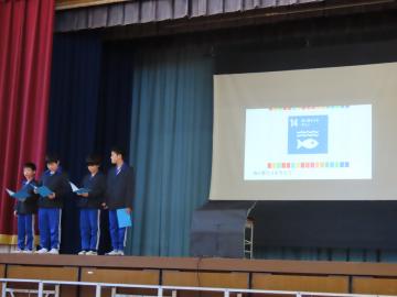 体育館の壇上でSDGsの発表をする高学年の児童たちの様子