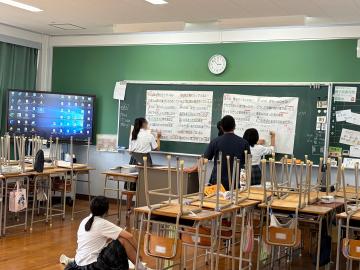 生徒と教師がクラスでの合唱練習を準備する様子