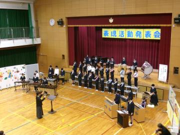 体育館の壇上で、3年生から6年生の児童たちが合奏している様子