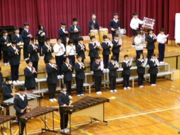 体育館の壇上で、児童たちがリコーダーを吹いている様子