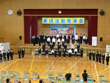 体育館の壇上で、児童たちが全校合唱をしている様子