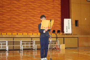 体育館で、代表の生徒がはじめの言葉を言っている様子